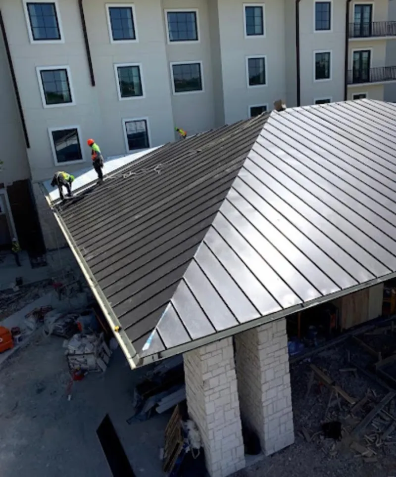Crew installing standing seam metal roof panels on a commercial project in Northampton